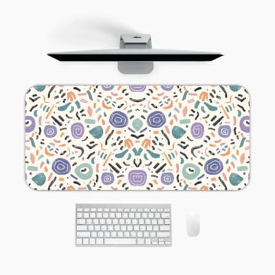 Infidu Playful Desk Pad with a white background and scattered colorful shapes in light blue, purple, peach, and black. A desk pad under the computer