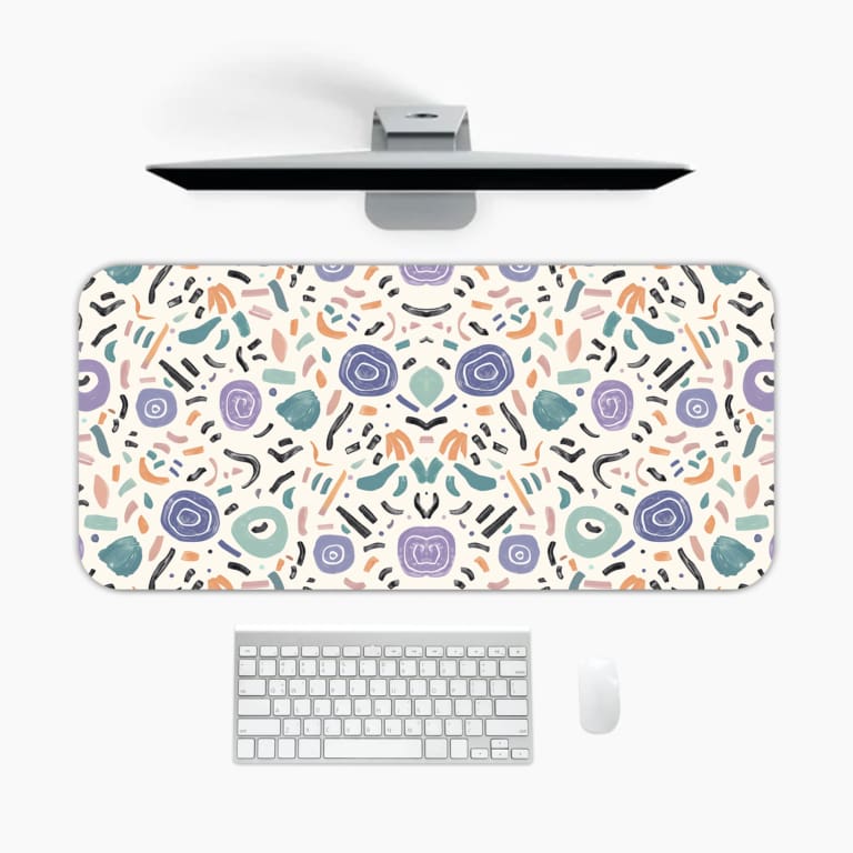 Infidu Playful Desk Pad with a white background and scattered colorful shapes in light blue, purple, peach, and black. A desk pad under the computer