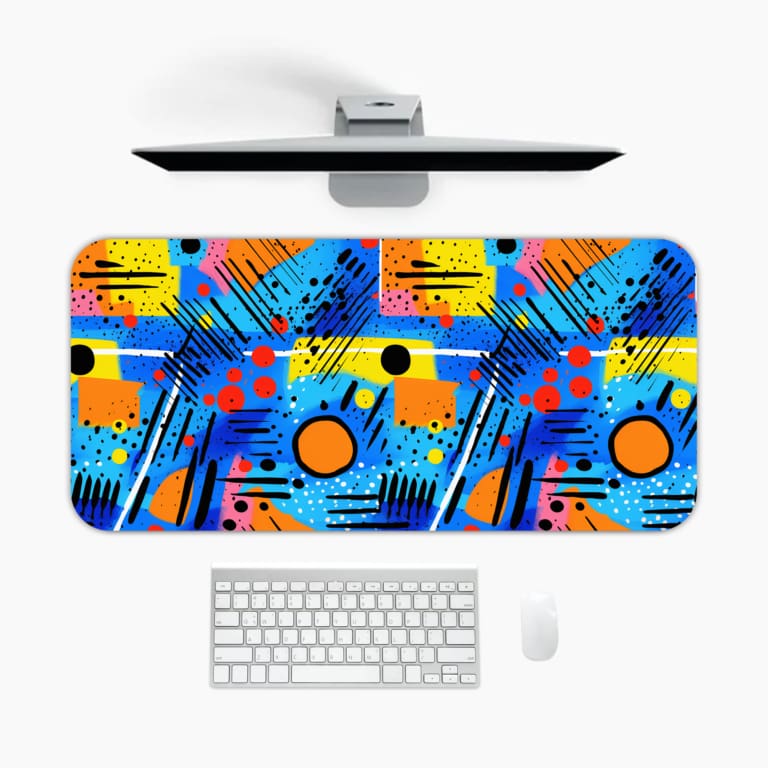 Infidu desk pad with a bright abstract design in blue, yellow, orange, and red, featuring various shapes against a blue background. A desk pad under the computer