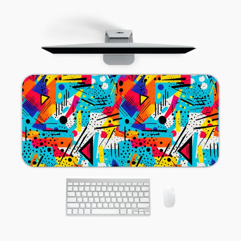 Infidu Colorful Desk Pad shows vibrant geometric shapes in blue, yellow, red, and pink on a lively abstract background. A desk pad under the computer