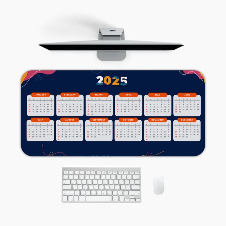 Desk pad with dark blue background, yellow "2025," orange-bordered calendar layout, and pink and purple accents A desk pad under the computer