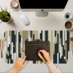 Infidu desk pad with vertical pixel stripe design in beige, black, gray, and white for a modern vintage art-inspired look.