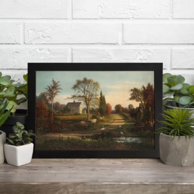 Infidu vintage wall art features a serene countryside scene with a charming house, tall trees, and a soft blue sky. displayed on the wall art in a black frame