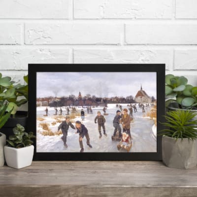 Vintage winter ice skating scene featuring people skating on a frozen lake with a distant village backdrop. Perfect for vintage wall decor. displayed on the table in a black frame
