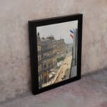Vintage wall art of a Paris street scene with French flags, horse-drawn carriages, pedestrians, and elegant buildings in soft muted colors. displayed on the wall