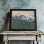 Infidu vintage wall art of snowy mountains in soft blue tones with a misty sky and forested valley. displayed on the wall