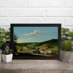 Vintage countryside wall art with hills, houses, and blue sky. displayed on the wall