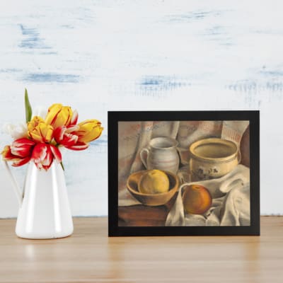 Vintage still-life wall art featuring rustic bowls, a pitcher, and lemons on a wooden surface with a soft cloth. displayed on the table in a black frame