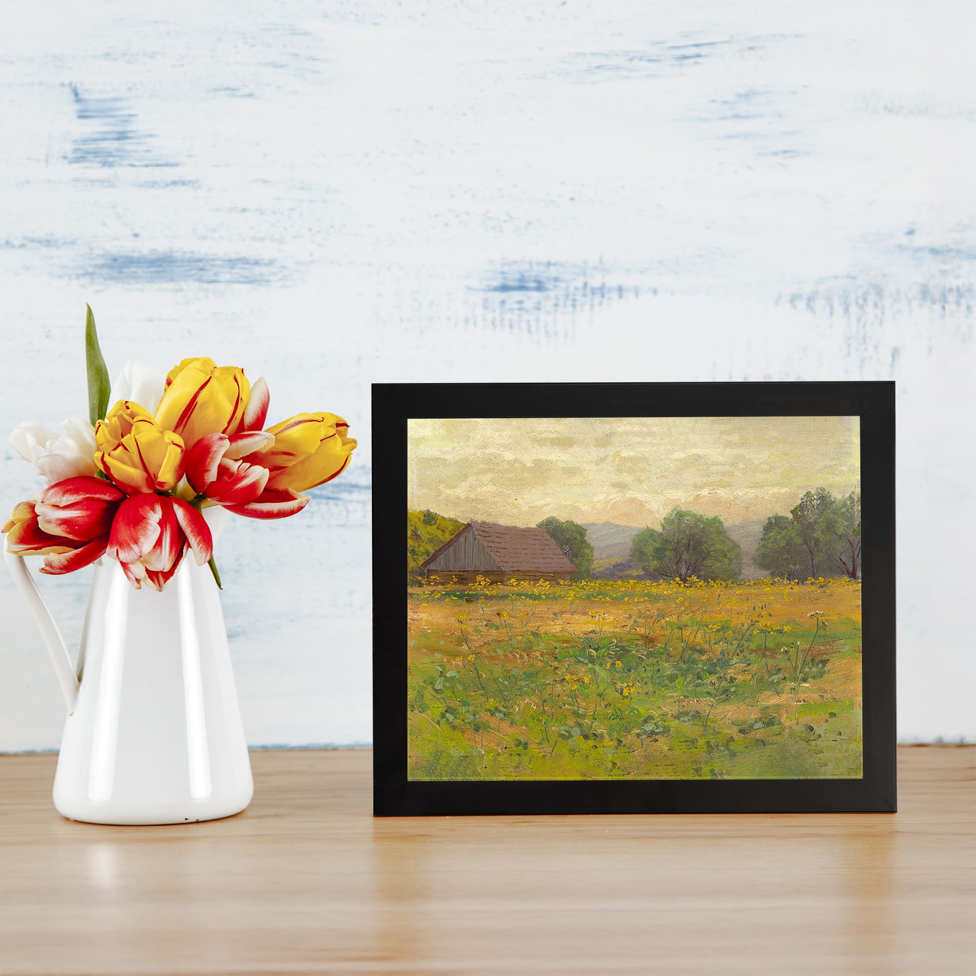 Vintage wall art of a peaceful countryside scene with a field, small cottage, and trees in soft natural colors of yellow, green, and brown. displayed on the wall