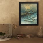 Vintage wall art of a snowy cottage on a hillside with bare trees, frozen stream, and soft blue tones in a peaceful winter scene. displayed on the wall