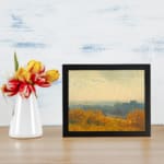 Vintage wall art of an autumn city view with golden trees, a hazy sky, and a soft, distant town skyline. displayed on the wall