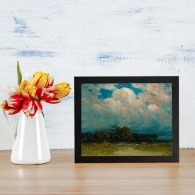 Vintage cloudscape wall art with soft pink, gray, and white clouds over a calm green landscape. displayed on the wall