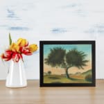 Vintage wall art of a lone tree in a peaceful landscape with soft green hills, distant hills, and a gentle blue and peach sky. displayed on the wall