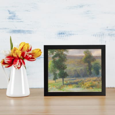 Vintage countryside wall art with yellow flower fields, tall green trees, and a soft cloudy sky in natural tones. displayed on the wall
