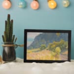 Infidu vintage wall art with a peaceful mountain, a grassy field, and soft natural colors in a calming countryside scene. displayed on the wall