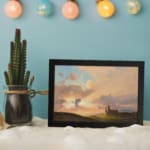Vintage sunset countryside scene with soft colors, a small building on a green hill, and glowing rays of sunlight. displayed on the wall