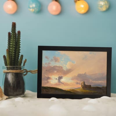 Vintage sunset countryside scene with soft colors, a small building on a green hill, and glowing rays of sunlight. displayed on the wall