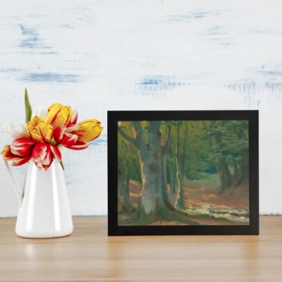 Vintage forest wall art with tall trees, earthy tones, and cool green and blue colors creating a serene, natural atmosphere. displayed on the table in a black frame