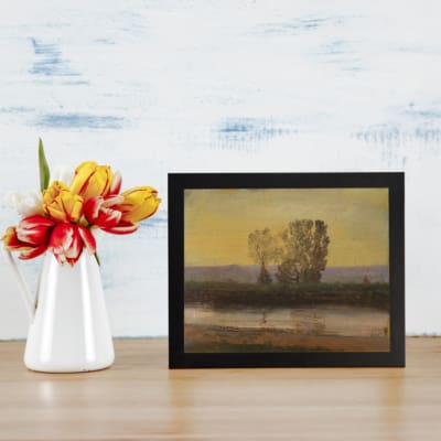 Vintage wall art featuring a serene landscape with trees, hills, and a calming sky. Perfect for nature lovers and vintage decor enthusiasts. displayed on the table in a black frame