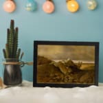 Vintage wall art of a fallen tree on a rocky hillside with earthy tones and a soft sky. displayed on the wall
