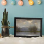 Vintage reflective landscape wall art with soft grays, blues, and greens, showing water reflections, bare trees, and low hills. displayed on the wall