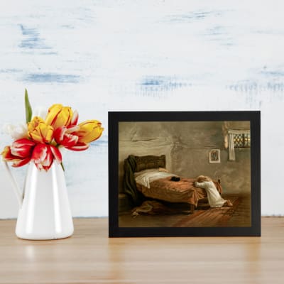 Infidu Vintage Wall Art Rustic bedroom scene with muted earthy tones, featuring a serene bed and kneeling figure. displayed on the table in a black frame
