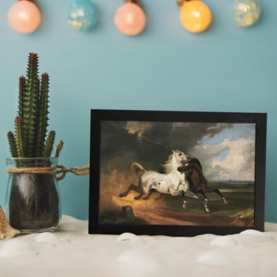 Vintage wall art of a white and dark brown horse in motion under a stormy sky with dramatic clouds and open fields. displayed on the wall