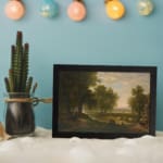 Vintage wall art of peaceful countryside with trees, river, and cattle displayed on the wall