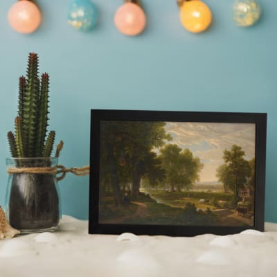 Vintage wall art of peaceful countryside with trees, river, and cattle displayed on the wall
