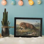 Vintage wall art of a fox crouched over a rabbit in a grassy countryside field with natural earthy tones and peaceful rural background. displayed on the wall
