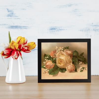 Vintage floral wall art of a pastel roses bouquet with creamy white and pink roses, lush green leaves, and a muted beige background. displayed on the table in a black frame
