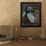 Vintage wall art of two women in traditional clothing by a wooden fence in a rustic countryside setting. displayed on the wall