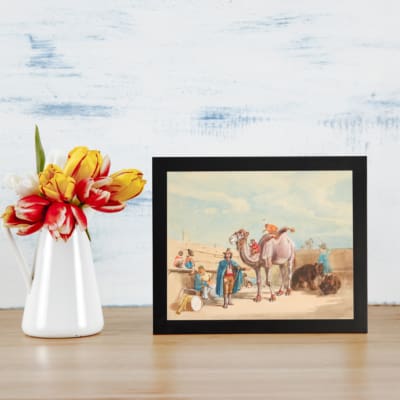 Vintage wall art featuring a camel with a rider, festival scene with colorful figures, and desert architecture in soft beige and blues. displayed on the wall