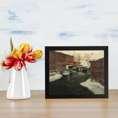 Vintage winter river scene with brick buildings and snowy rooftops by Infidu. displayed on the wall