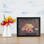 Vintage wall art of pink and yellow flowers in a white bowl with a brown textured background, framed in black. displayed on the wall