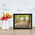 Vintage wall art of a sunny terrace with trees, wooden floor, and distant hills, capturing a peaceful outdoor scene. displayed on the wall