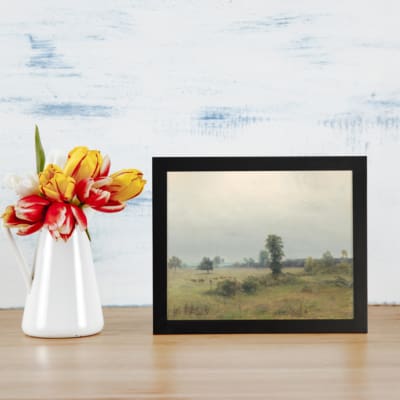 Infidu vintage wall art of a quiet countryside with soft green fields, trees, and a cloudy sky in muted tones. displayed on the wall