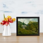 Vintage countryside wall art with green hills, trees, and a gray-roofed house in a calm rural setting. displayed on the wall