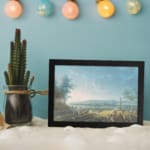 Vintage lakeside scene with people, hills, and a calm sky in soft tones. displayed on the wall