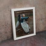 Vintage wall art of two women in traditional clothing by a wooden fence in a rustic countryside setting. displayed on the wall