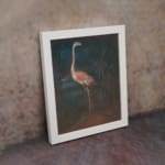 Vintage wall art of a pink flamingo standing in a dark, natural setting with elegant contrast and tropical plants in the background. displayed on the wall