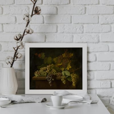Vintage rustic wall art with grapes and leaf design on a dark background in earthy tones of green, brown, and gold. displayed on the wall in a white frame