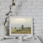Infidu vintage wall art of a quiet countryside with soft green fields, trees, and a cloudy sky in muted tones. displayed on the wall