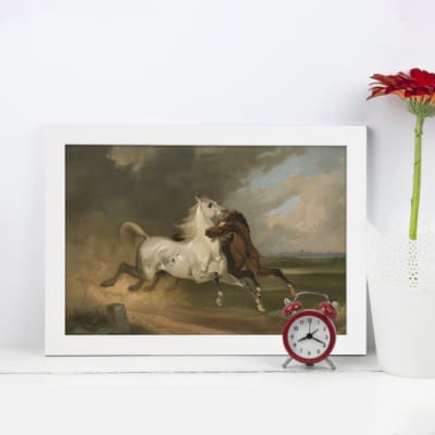 Vintage wall art featuring two horses, one white and one brown, in a pastoral landscape with earthy tones and a cloudy grayish-blue sky. displayed on the wall in a white frame