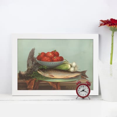 Vintage wall art still life featuring a bowl of tomatoes, green onions, and leafy vegetables on a wooden table with a light blue background. displayed on the wall in a white frame