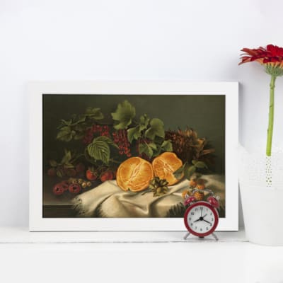 Vintage wall art of a classic fruit still life scene featuring sliced lemons, grapes, and vibrant produce on a dark background with white cloth. displayed on the wall in a white frame