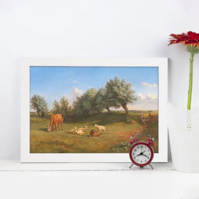 Vintage wall art featuring a pastoral landscape with cows, trees, and green grass, evoking a peaceful countryside atmosphere. displayed on the wall in a black frame