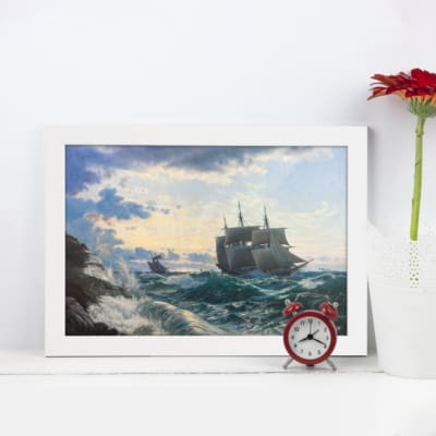 Vintage wall art of a sailing ship navigating rough ocean waves with a dramatic seascape background. Perfect for nautical-themed decor. displayed on the wall in a white frame