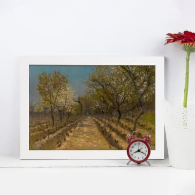 Vintage wall art featuring a scenic tree-lined pathway with earthy tones of green, yellow, blue, and brown under a slightly clouded sky. displayed on the wall in a white frame kept on the mat