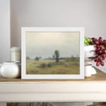 Infidu vintage wall art of a quiet countryside with soft green fields, trees, and a cloudy sky in muted tones. displayed on the wall